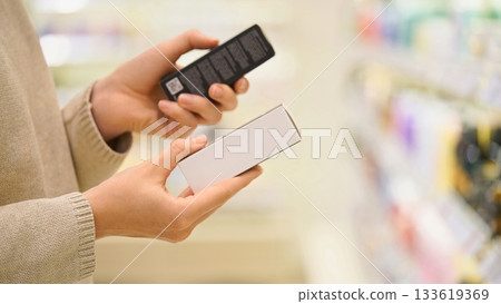 Woman reading ingredient labels, comparing and choosing between cosmetic products, cream or serum in a beauty store, focusing on packaging and information. The concept of conscious choice Woman reading ingredient labels, comparing and choosing between cosmetic products, cream or serum in a beauty store, focusing on packaging and information. The concept of conscious choice 133619369