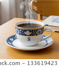 Steaming cup of coffee with blue ornate pattern and letter S on saucer hot drink 133619423
