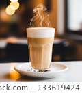 Steaming latte with foamy milk in a tall glass on a saucer coffee hot drink 133619424