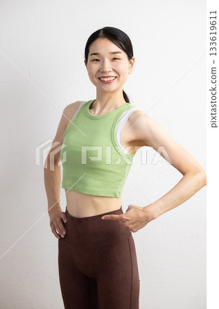 一位身穿瑜珈服的微笑女子指著自己的腰部 133619611