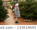 Father and daughter choose a Christmas tree at a forestry. 133619693