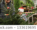 Father and daughter choose a Christmas tree at a forestry. 133619695