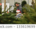Father and daughter choose a Christmas tree at a forestry. 133619699