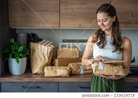 Woman holding a labeled grocery bag with the word Recept, meaning recipe in another language. Concept of convenient meal kit delivery with pre-portioned, ready-to-cook ingredients. Woman holding a labeled grocery bag with the word Recept, meaning recipe in another language. Concept of convenient meal kit delivery with pre-portioned, ready-to-cook ingredients. 133619719