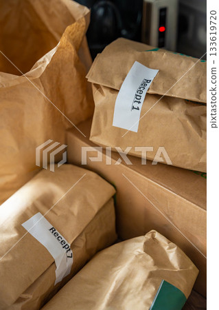 Close-up of brown paper bags with meal kits labeled Recept or Recipe. Subscription-based food delivery sorted by recipes. 133619720
