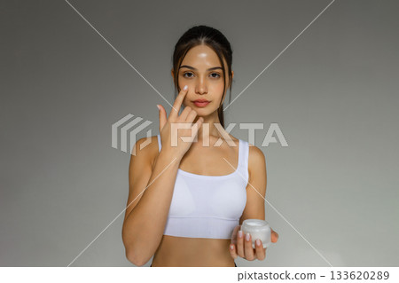 Young brunette woman applying face cream, skincare routine, moisturizing treatment, beauty care, healthy glowing skin, cosmetic product usage for daily skincare. Young brunette woman applying face cream, skincare routine, moisturizing treatment, beauty care, healthy glowing skin, cosmetic product usage for daily skincare. 133620289