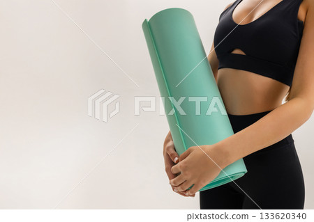 Close up of woman holding yoga mat, fitness gear, yoga equipment for training, pilates workout, gym essentials, healthy lifestyle and active routine on beige background. Close up of woman holding yoga mat, fitness gear, yoga equipment for training, pilates workout, gym essentials, healthy lifestyle and active routine on beige background. 133620340