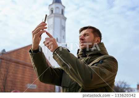 Man holding smartphone and taking photo of tower outdoors 133620342