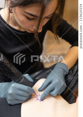 tattoo artist working on a woman chest design in a studio, showing the process of professional tattooing, precision, sterile gloves and cosmetic procedure atmosphere. tattoo artist working on a woman chest design in a studio, showing the process of professional tattooing, precision, sterile gloves and cosmetic procedure atmosphere. 133620354