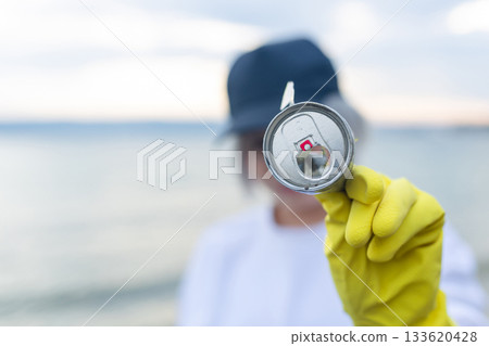 volunteer showing a collected metal can during beach cleanup, highlighting pollution, ecology, environment protection, sustainability and coastal awareness. volunteer showing a collected metal can during beach cleanup, highlighting pollution, ecology, environment protection, sustainability and coastal awareness. 133620428