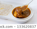Close-up of curry in a white lunch box being picked up with a spoon 133620837