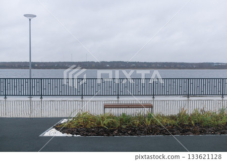 Bench on the embankment of the lake in cloudy weather. Bench on the embankment of the lake in cloudy weather. 133621128