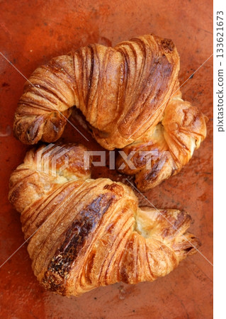 Two croissant pastries over orange clay Two croissant pastries over orange clay 133621673