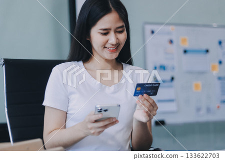 Online payment, Hands of woman holding a credit card and using smart phone for online shopping Online payment, Hands of woman holding a credit card and using smart phone for online shopping 133622703