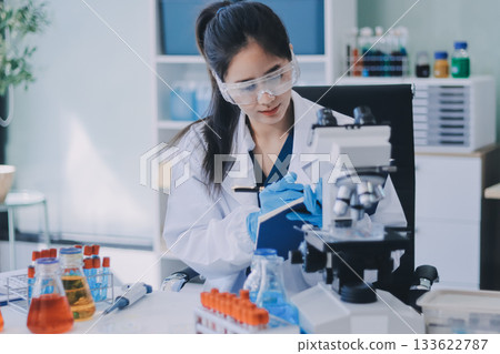 Portrait, science and happy woman on laptop in lab to research chemistry, test or innovation. Microscope, scientist and face of medical doctor in goggles for microbiology, healthcare or pharma study 133622787