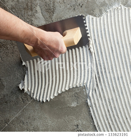construction notched trowel with white cement 133623191