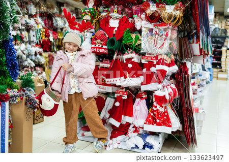 Young caucasian girl shopping for Christmas costumes in festive store 133623497