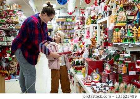 Caucasian female adult with caucasian female child shopping for christmas decorations 133623499