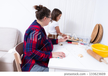 Mother and daughter baking together in kitchen setting with dough preparation Mother and daughter baking together in kitchen setting with dough preparation 133623609