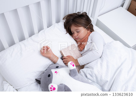 Young caucasian girl sleeping peacefully with stuffed cat in white bed Young caucasian girl sleeping peacefully with stuffed cat in white bed 133623610
