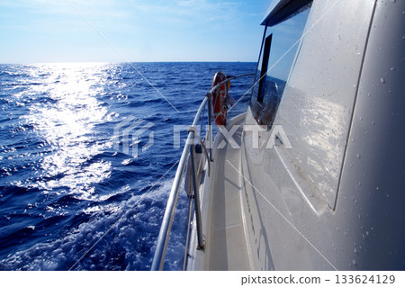 Boat side sailing in blue sea sun reflection 133624129