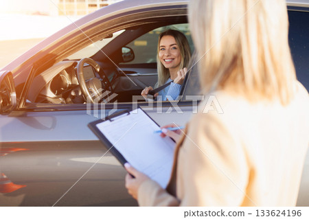 Young Learner Driver Adjusting Seatbelt While Instructor Takes Notes 133624196