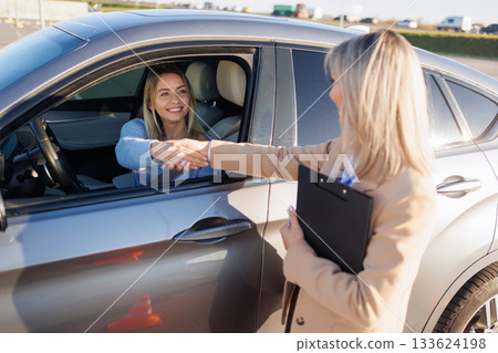 Learner Driver Shaking Hands with Instructor after Successful Driving Test 133624198