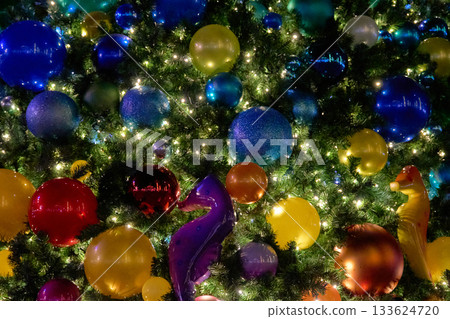 A Christmas tree glows with bright lights and glossy multicolor ornaments around a purple seahorse. The playful marine theme creates a cheerful holiday close-up. A Christmas tree glows with bright lights and glossy multicolor ornaments around a purple seahorse. The playful marine theme creates a cheerful holiday close-up. 133624720