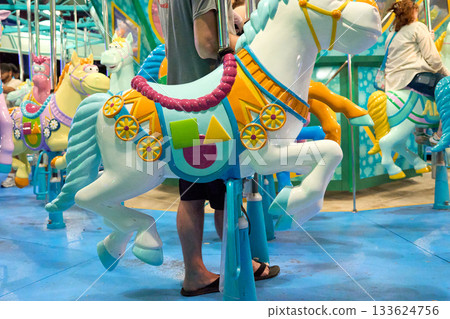Shiny horse figures on a lively children's carousel. Warm pastel colors set a happy family vibe. 133624756