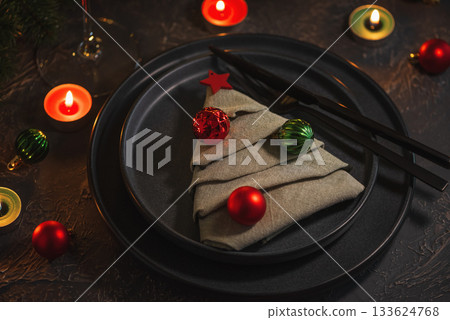 Christmas Table Setting with Tree-Shaped Napkin, Utensils, Ornaments and Tealight Candles Christmas Table Setting with Tree-Shaped Napkin, Utensils, Ornaments and Tealight Candles 133624768