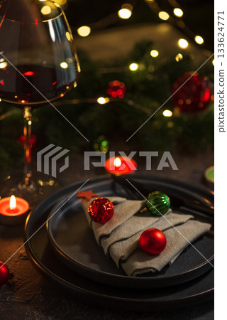 Christmas Table Setting with Tree-Shaped Napkin, Utensils, Ornaments and Tealight Candles Christmas Table Setting with Tree-Shaped Napkin, Utensils, Ornaments and Tealight Candles 133624771