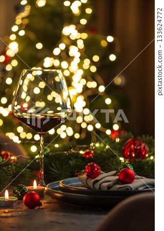 Christmas Table Setting with Wineglasses with Red Wine against Christmas lights Christmas Table Setting with Wineglasses with Red Wine against Christmas lights 133624772