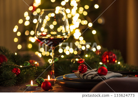 Christmas Table Setting with Wineglasses with Red Wine against Christmas lights Christmas Table Setting with Wineglasses with Red Wine against Christmas lights 133624773
