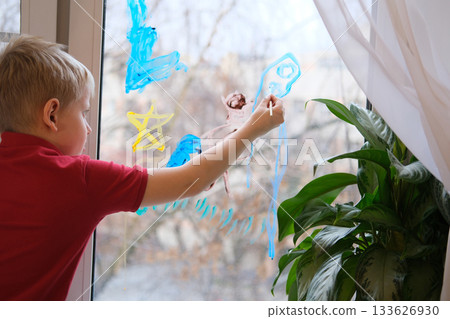 Young boy drawing on window with colorful paint Young boy drawing on window with colorful paint 133626930