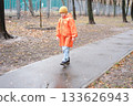 Boy walking alone on a wet park path during autumn 133626943