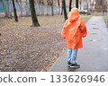 Child walking alone on wet path in autumn park 133626946