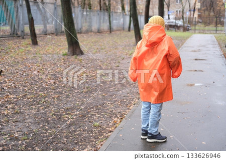 Child walking alone on wet path in autumn park 133626946