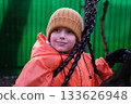 Young boy smiling playing on playground swing 133626948