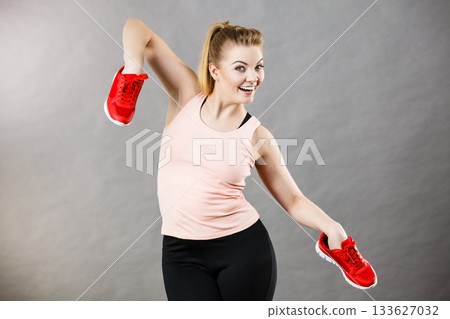 Happy woman presenting sportswear trainers shoes Happy woman presenting sportswear trainers shoes 133627032