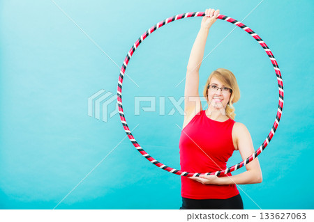 Fit woman with hula hoop doing exercise 133627063
