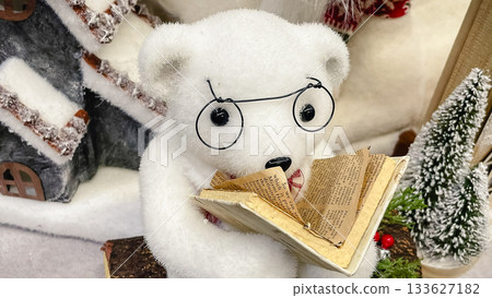 Adorable plush polar bear figurine with glasses reading a miniature book in a winter scene Adorable plush polar bear figurine with glasses reading a miniature book in a winter scene 133627182