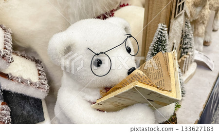 Adorable plush polar bear figurine with glasses reading a miniature book in a winter scene Adorable plush polar bear figurine with glasses reading a miniature book in a winter scene 133627183