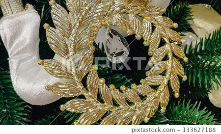 Luxury gold leaf wreath Christmas ornament with a sparkling crystal on a green fir branch Luxury gold leaf wreath Christmas ornament with a sparkling crystal on a green fir branch 133627188