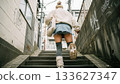 Back view of a casual woman running briskly up the stairs in an alley 133627347