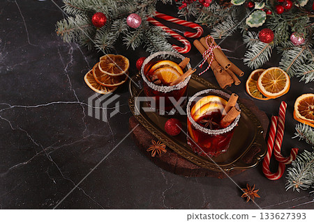 Warming winter drink in the cold season, festive Christmas grog, strong alcoholic or non-alcoholic cocktail on the festive table, mulled wine with spices, star anise, cranberries, orange, apple 133627393