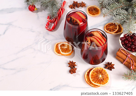 Warming winter drink in the cold season, festive Christmas grog, strong alcoholic or non-alcoholic cocktail on the festive table, mulled wine with spices, star anise, cranberries, orange, apple 133627405
