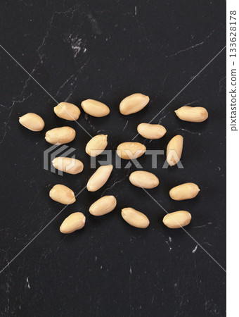 Group of peeled peanuts on black marble like board, closeup detail from above Group of peeled peanuts on black marble like board, closeup detail from above 133628178