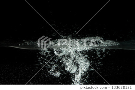 Water splashing as it's poured into aquarium tank, black background Water splashing as it's poured into aquarium tank, black background 133628181