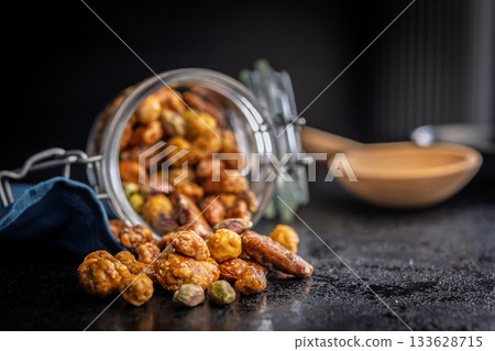 Nuts coated in sugar glaze on black table. 133628715