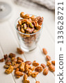 Nuts coated in sugar glaze in jar on white table. 133628721